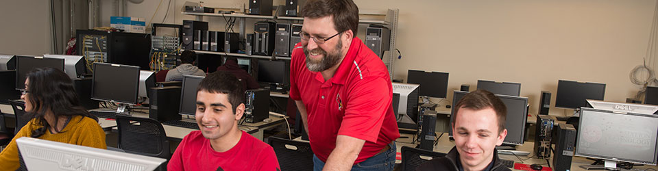 professor helping two students on computers